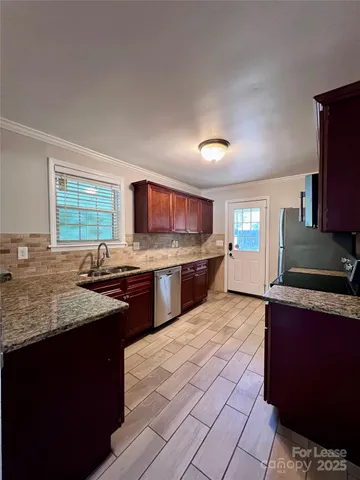 a kitchen with granite countertop a sink stove and cabinets