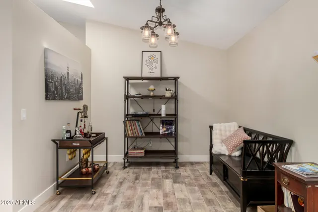 a view of a dining room and livingroom with furniture wooden floor a rug a flat screen tv a painting and a chandelier