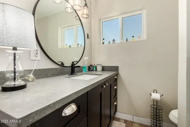 a bathroom with a granite countertop sink mirror vanity and toilet