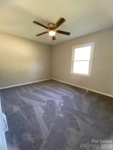 an empty room with a window and a fan