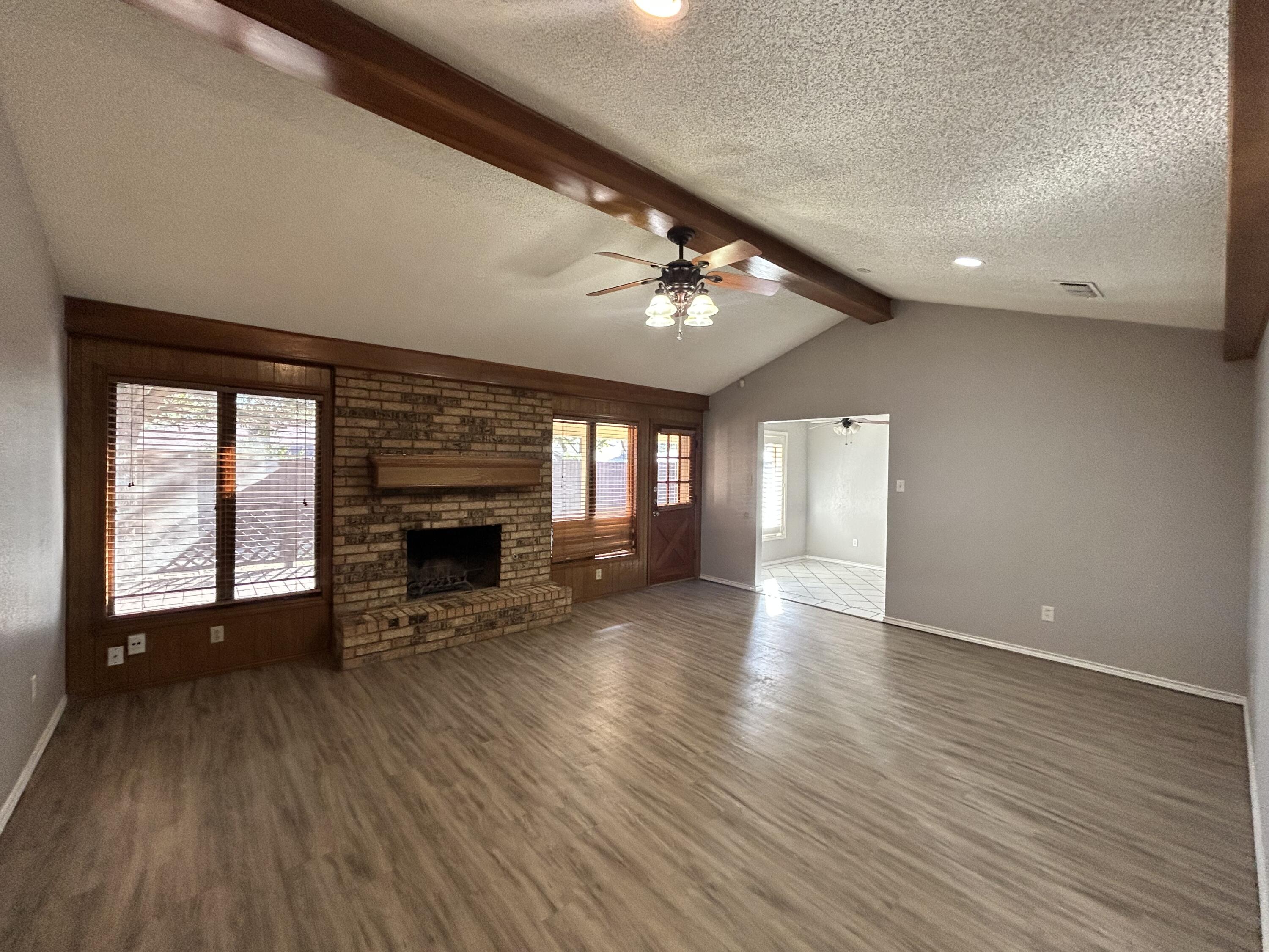 5517 89th Street Lubbock, TX 79424 - Photo 3 of 20 an empty room with wooden floor fireplace and windows