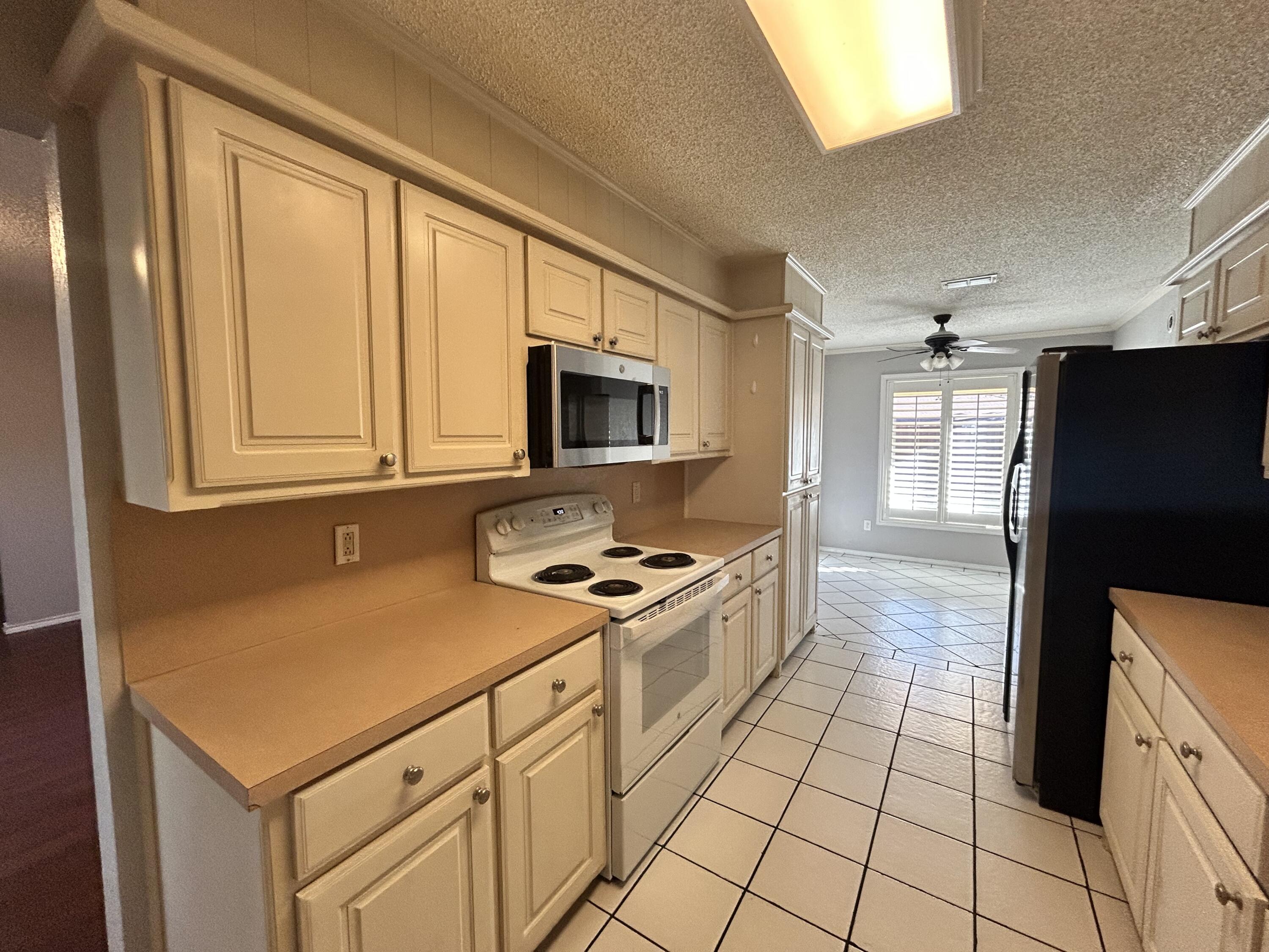 5517 89th Street Lubbock, TX 79424 - Photo 6 of 20 a kitchen with a stove a sink and a refrigerator