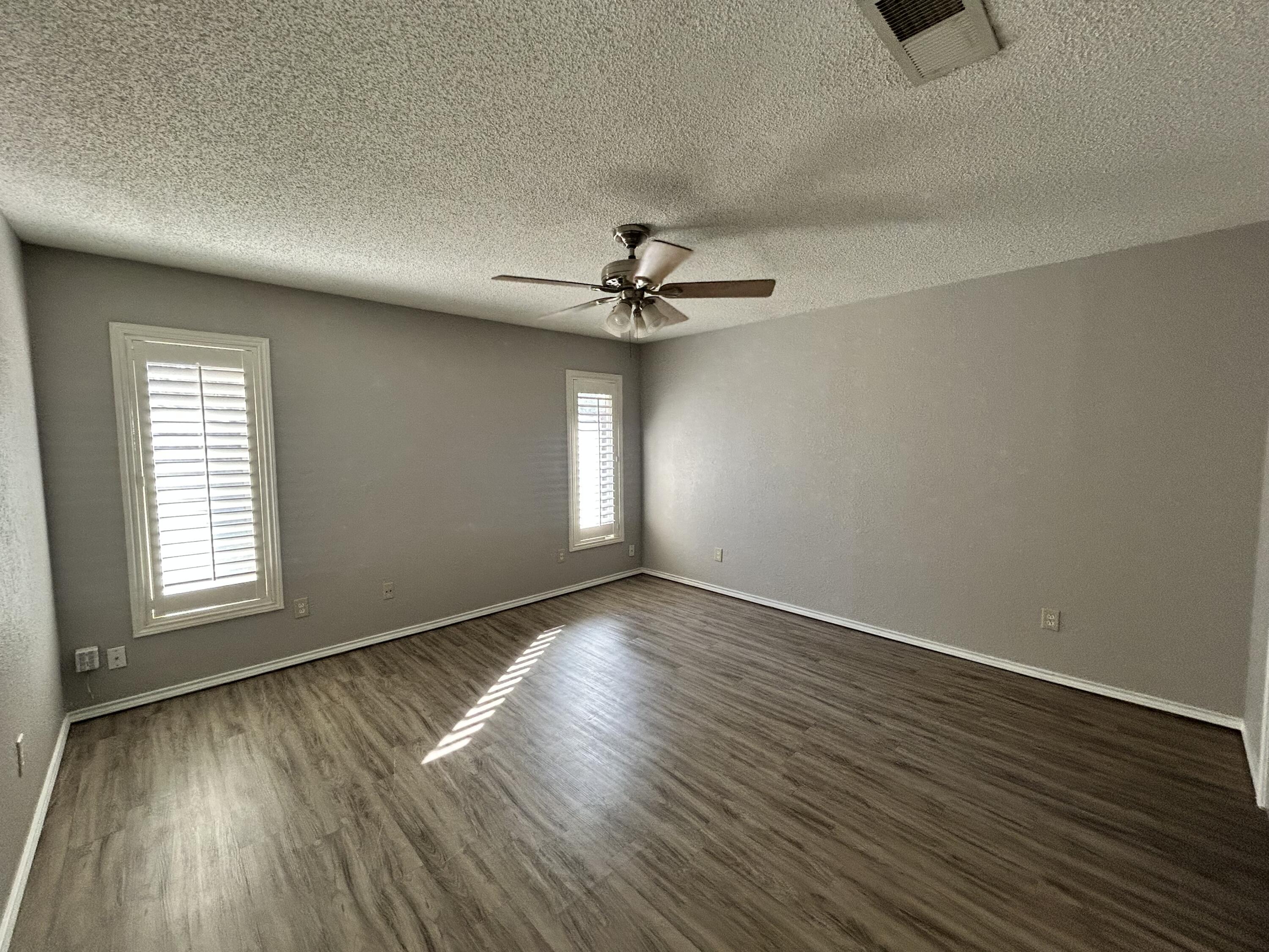 5517 89th Street Lubbock, TX 79424 - Photo 10 of 20 an empty room with wooden floor chandelier fan and windows