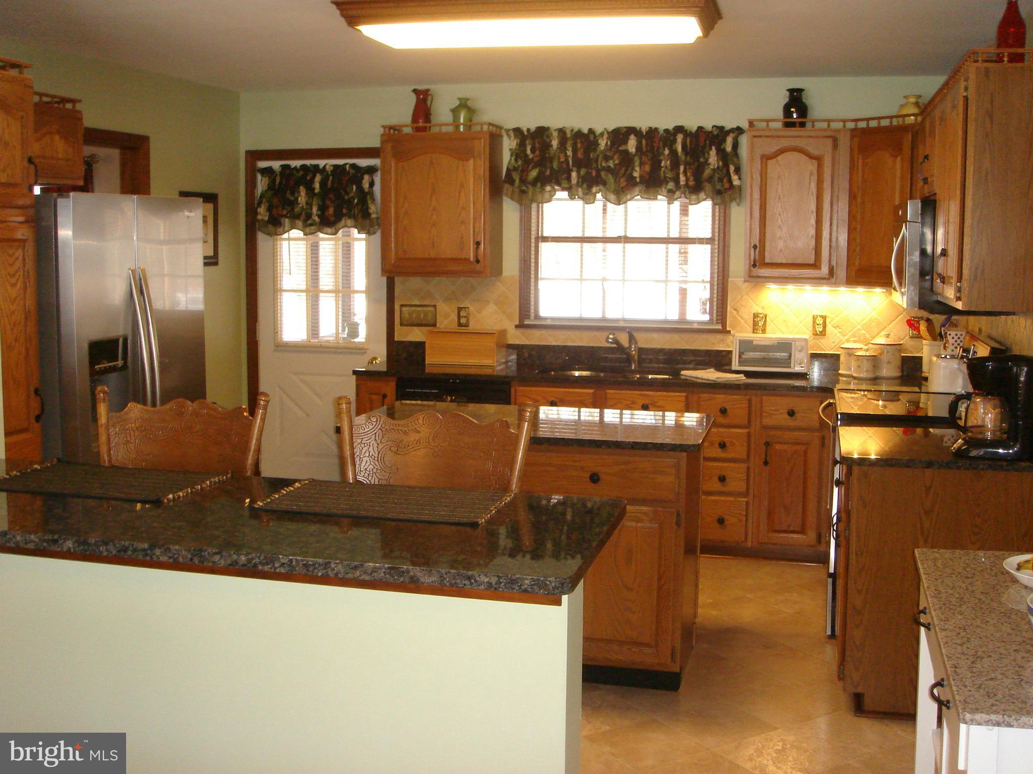 a kitchen with kitchen island granite countertop a sink a counter top space appliances and windows
