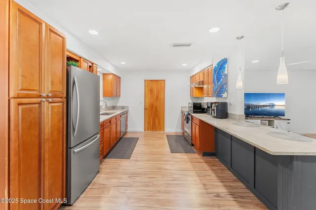 a large kitchen with stainless steel appliances a large counter top sink and wooden floor