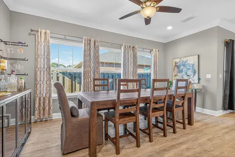 a large white dining hall with stainless steel appliances granite countertop a stove oven a dining table chairs with wooden floor