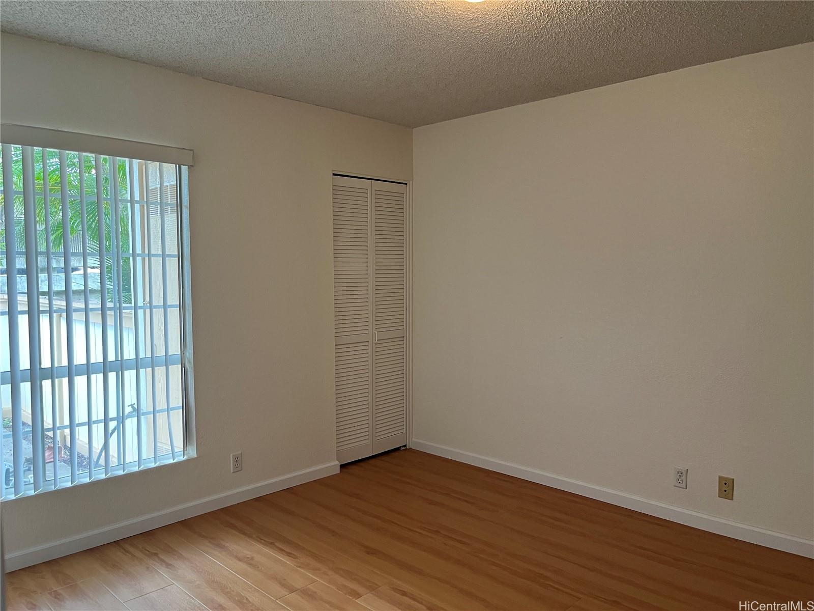 432 Mananai Place, Unit 18C Honolulu, HI 96818 - Photo 6 of 17 a view of an empty room with wooden floor and a window
