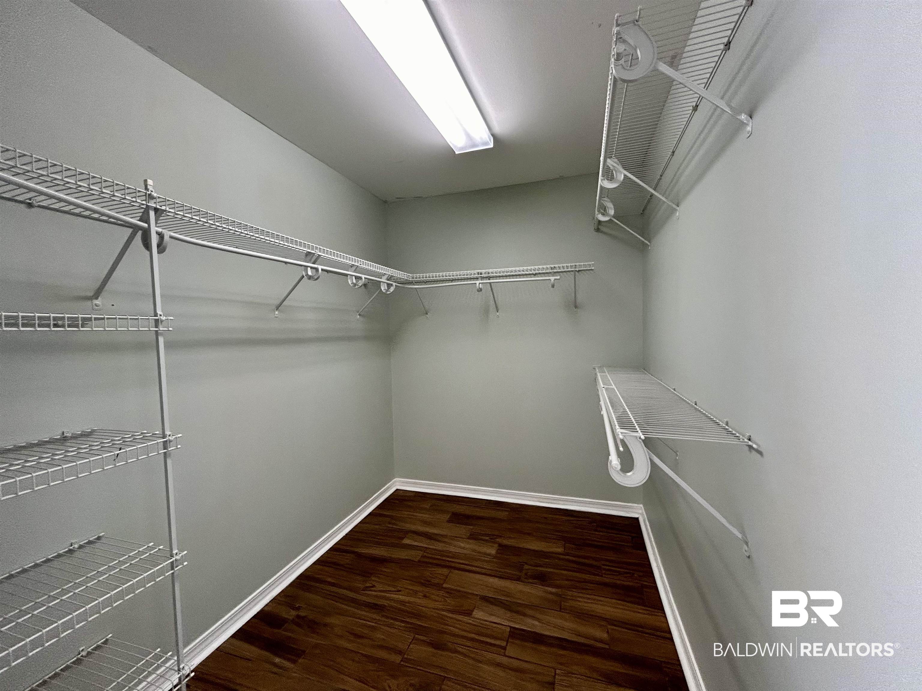 7198 Raintree Lane Gulf Shores, AL 36542 - Photo 14 of 33 Spacious closet featuring wood-finish flooring, ample wire shelving, integrated hanging rods, and an overhead fluorescent light fixture