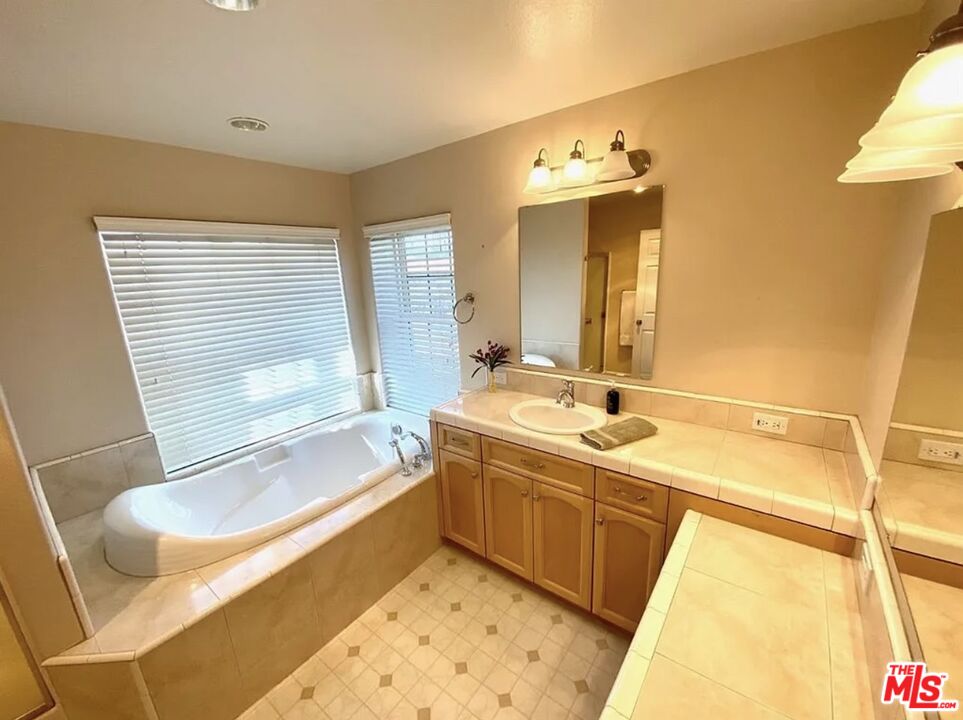 7173 Barker Road Oak Hills, CA 92344 - Photo 24 of 26 a bathroom with a tub sink and mirror
