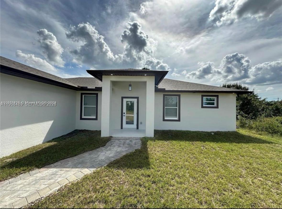 868 Cervantes Street East Lehigh Acres, FL 33974 - Photo 2 of 18 a front view of a house with garden