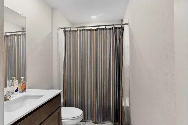 a bathroom with a sink a toilet a mirror and shower curtain