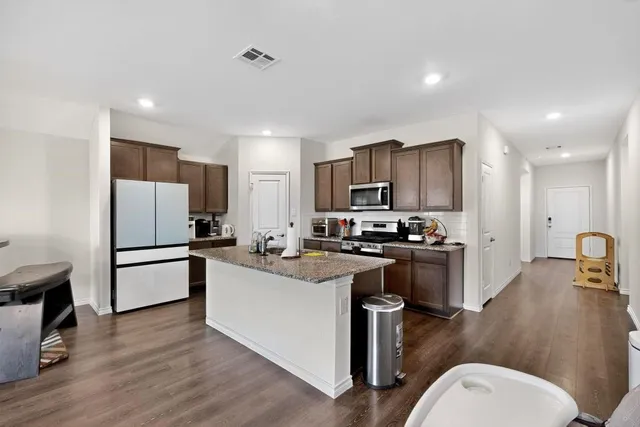 a kitchen with refrigerator a sink and chairs