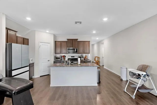 a kitchen with stainless steel appliances granite countertop a table chairs refrigerator and microwave