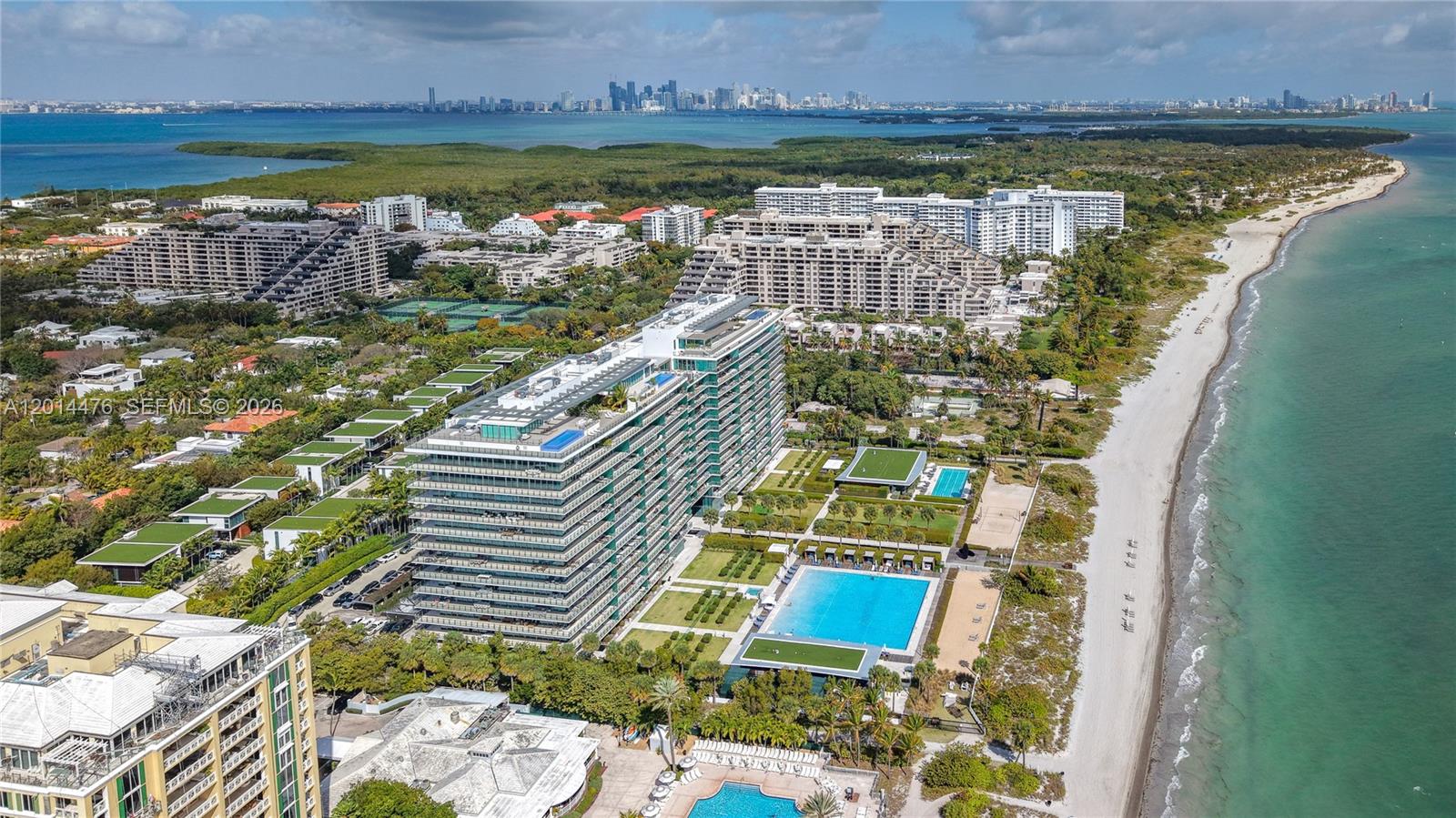 360 Ocean Drive, Unit 1106S Key Biscayne, FL 33149 - Photo 49 of 67 Aerial Waterfront Perspective – This sweeping view shows the building set between the beach and lush residential surroundings, with the skyline visible across the water. The image emphasizes the property’s high-end coastal environment.