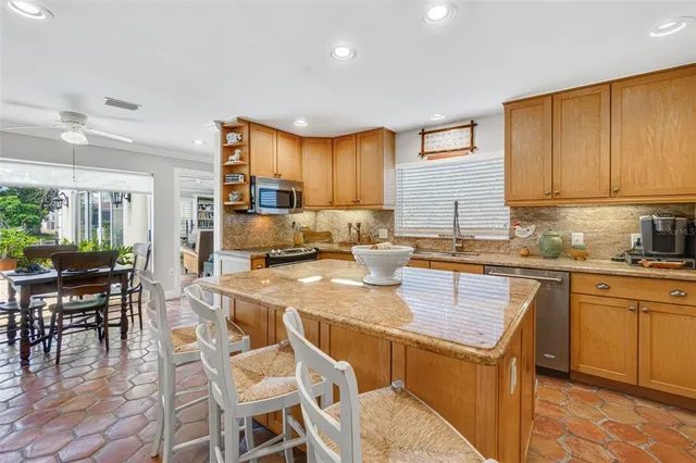 a kitchen with granite countertop a table chairs microwave and cabinets
