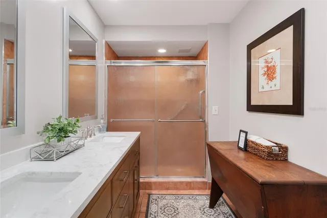 a bathroom with a granite countertop sink a mirror and a shower