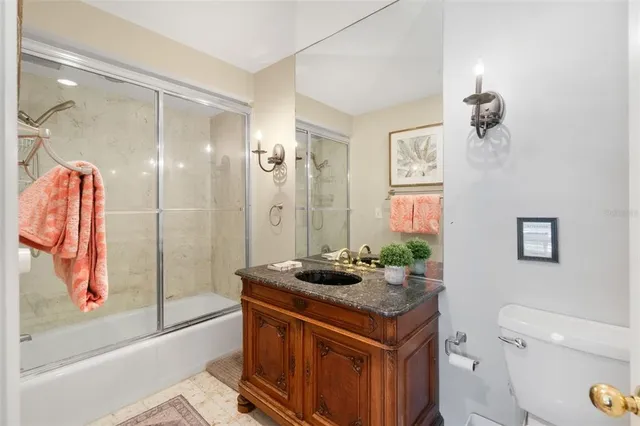 a bathroom with a granite countertop sink a toilet a mirror and shower