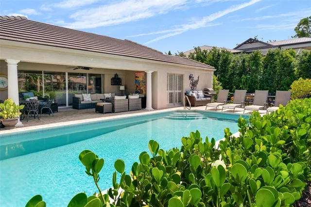 a view of a house with swimming pool lawn chairs and a yard