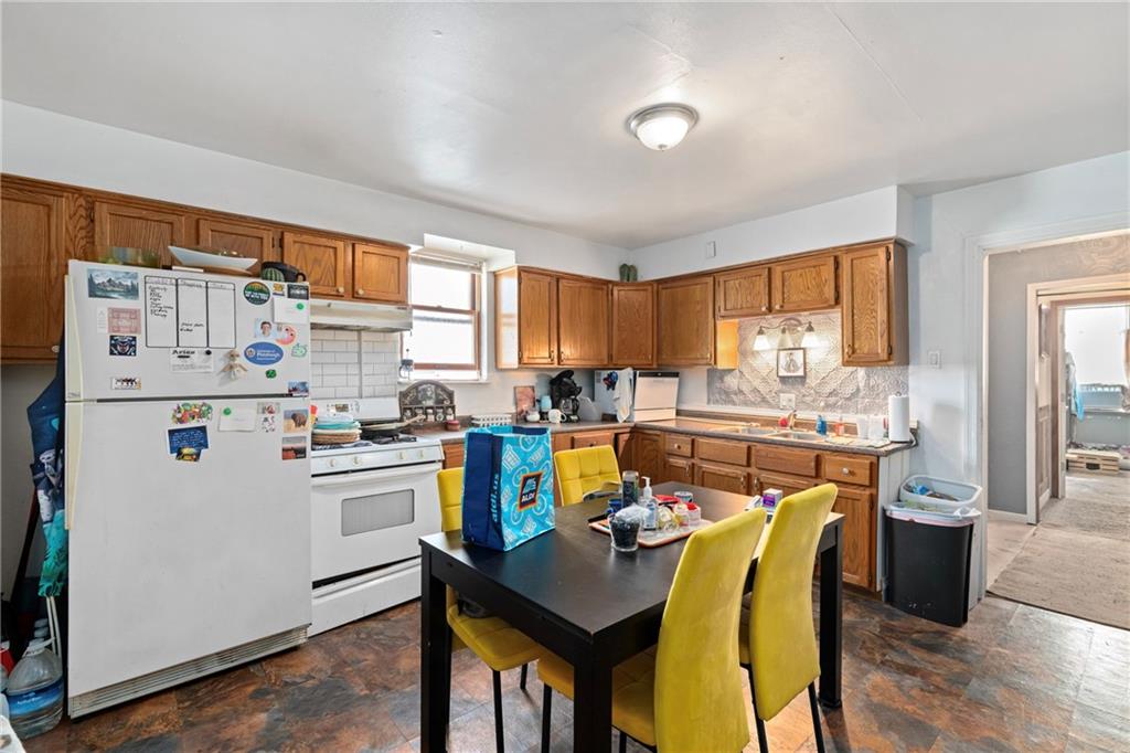 2123 Lautner Street Pittsburgh, PA 15212 - Photo 21 of 32 a kitchen with stainless steel appliances kitchen island granite countertop a stove a refrigerator a sink dishwasher a dining table and chairs with wooden floor