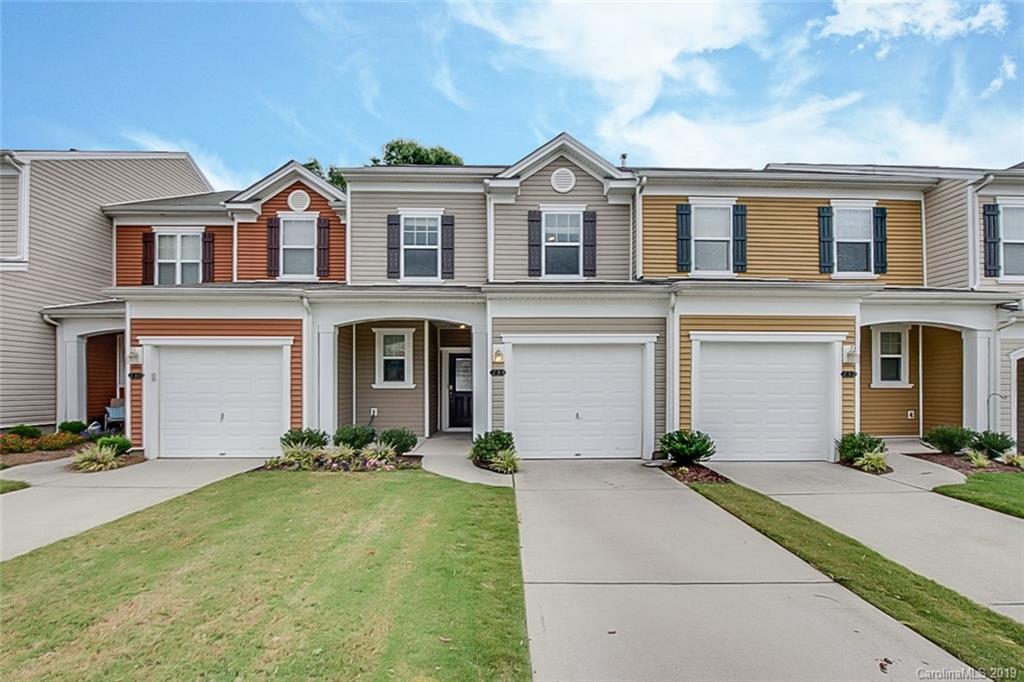 a front view of a house with yard and parking