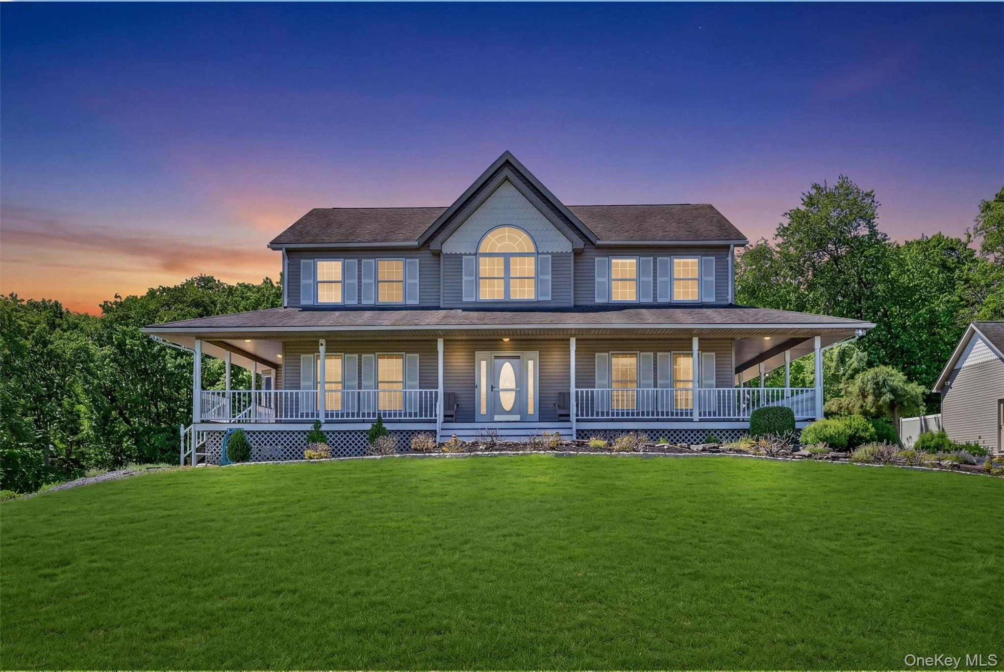 954 Ridgebury Road New Hampton, NY 10958 - Photo 1 of 45 Welcome to 954 Ridgebury Road in New Hampton, NY, a beautiful 44+ acre retreat that feels private and tucked away, yet is just 10 minutes from everyday conveniences. This twilight view captures the home’s warm and inviting first impression, with glowing windows, a wide front porch, and a peaceful setting that immediately sets the tone for the property.