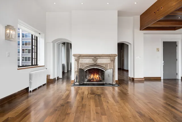 a view of an empty room with wooden floor fireplace and a window