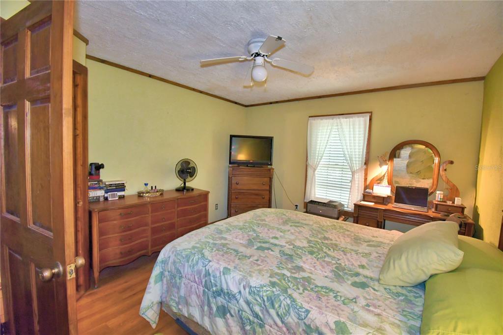 760 McClellan Road Frostproof, FL 33843 - Photo 15 of 72 a bedroom with a bed and a dresser with mirror