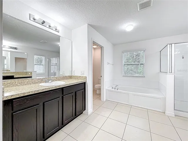 a spacious bathroom with a granite countertop sink mirror and bathtub