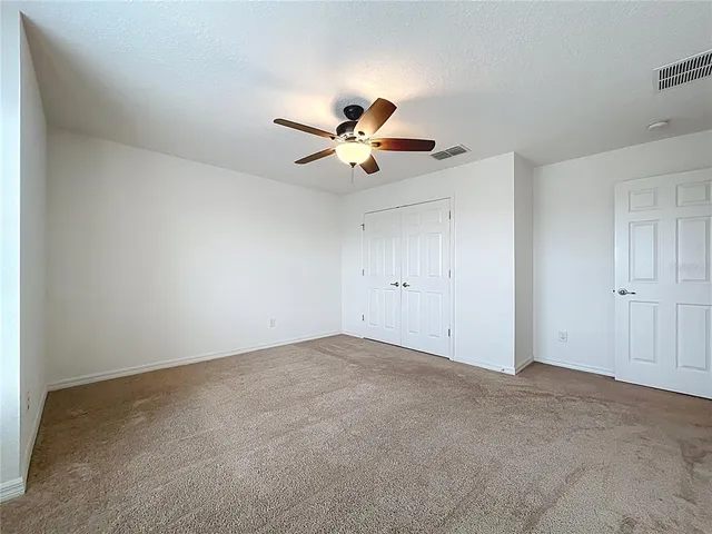 an empty room with windows and chandelier fan