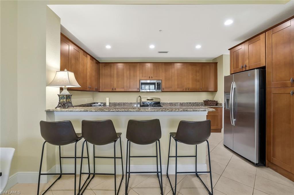 9209 Museo Circle, Unit 102 Naples, FL 34114 - Photo 5 of 18 a kitchen with stainless steel appliances granite countertop a refrigerator a stove a sink and a island