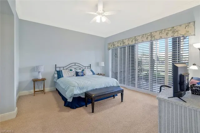 a bedroom with a bed lamp and a large window