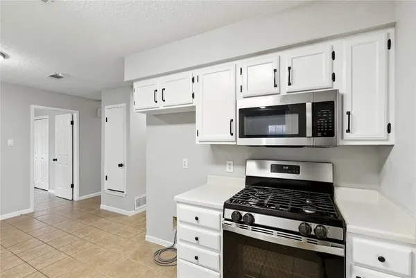 a kitchen with white cabinets and appliances