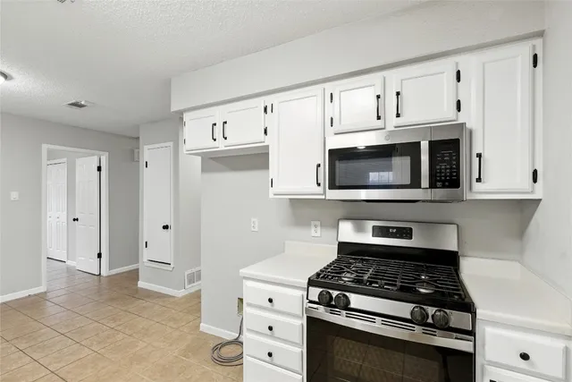a kitchen with white cabinets and appliances