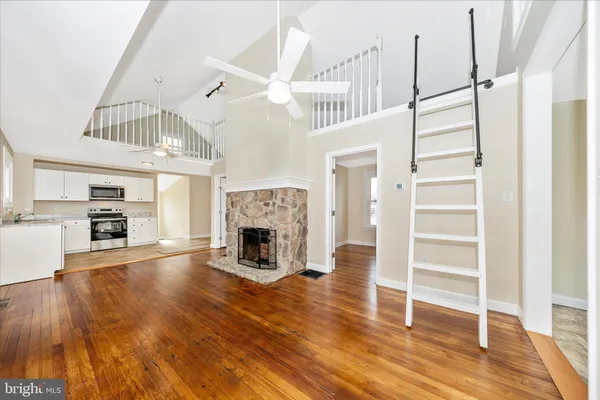 a view of a livingroom with wooden floor a fireplace and entryway