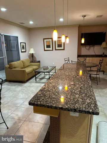 a view of a kitchen with kitchen island a stove a sink a refrigerator dining table and chairs