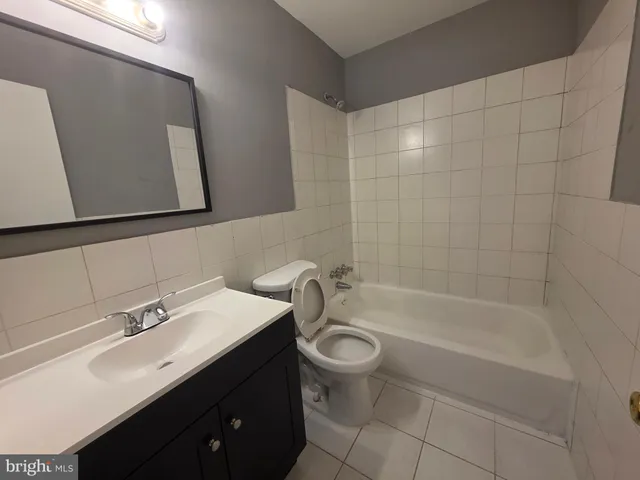 a bathroom with a bathtub shower sink mirror and toilet