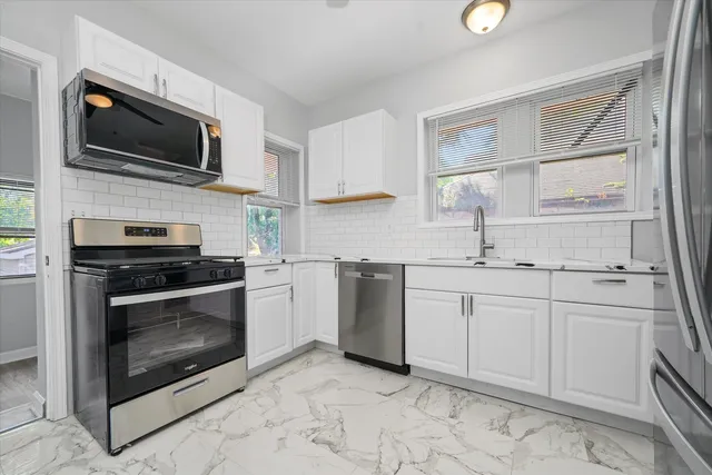 a kitchen with stainless steel appliances granite countertop a sink dishwasher stove and white cabinets