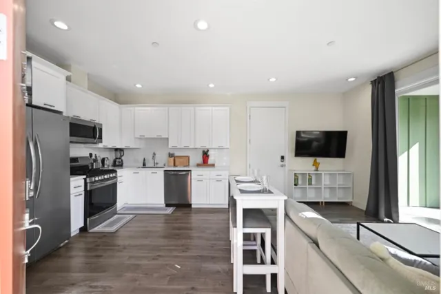 a kitchen with white cabinets and wooden floor