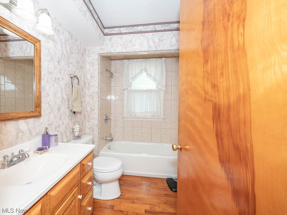 24093 Georgetown Road Homeworth, OH 44634 - Photo 11 of 35 Full bathroom with tiled shower / bath combo, hardwood floors, ornamental molding, and toilet. Behind the door is a large build-in linen closet.