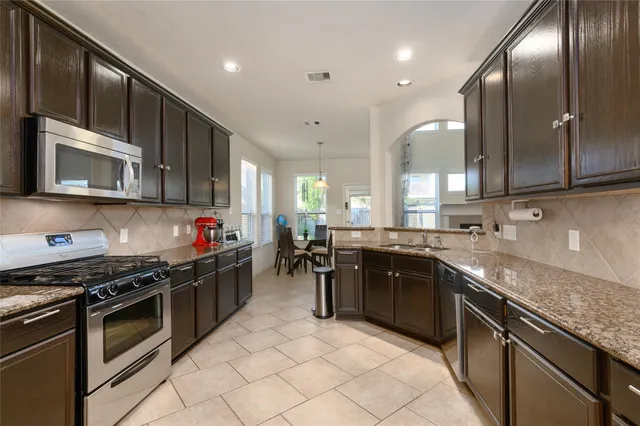 a large kitchen with stainless steel appliances granite countertop a sink stove and cabinets