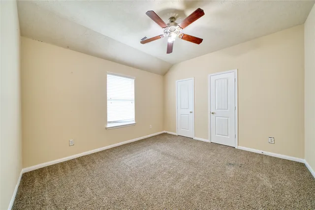 an empty room with windows and fan