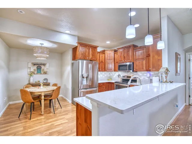 a kitchen with a refrigerator a stove a sink dishwasher with a dining table and chairs with wooden floor