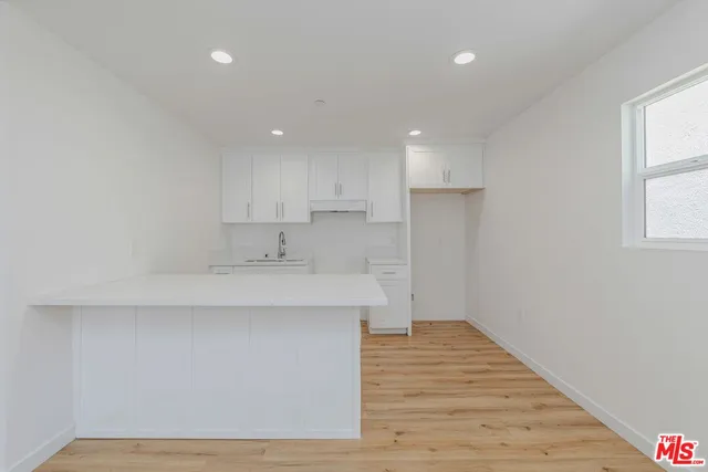 a kitchen with a sink wooden floor and a living room view