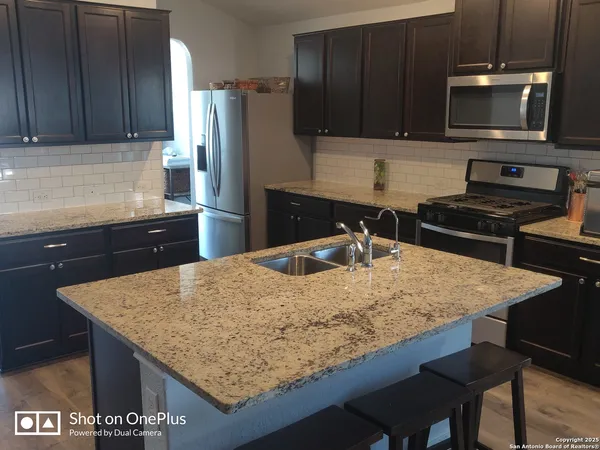 a kitchen with granite countertop wooden cabinets refrigerator and microwave