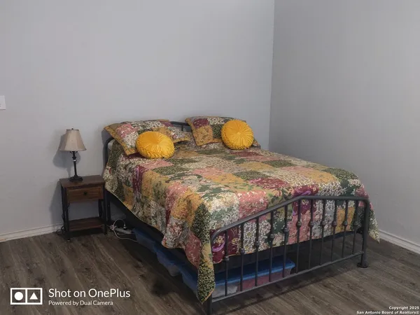 a bed sitting in a bedroom next to a lamp with wooden floor