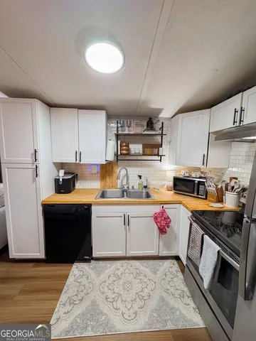 a kitchen with granite countertop a sink dishwasher stove top oven and cabinets with wooden floor