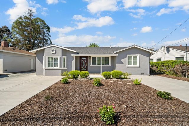 a front view of house with yard and trees in the background