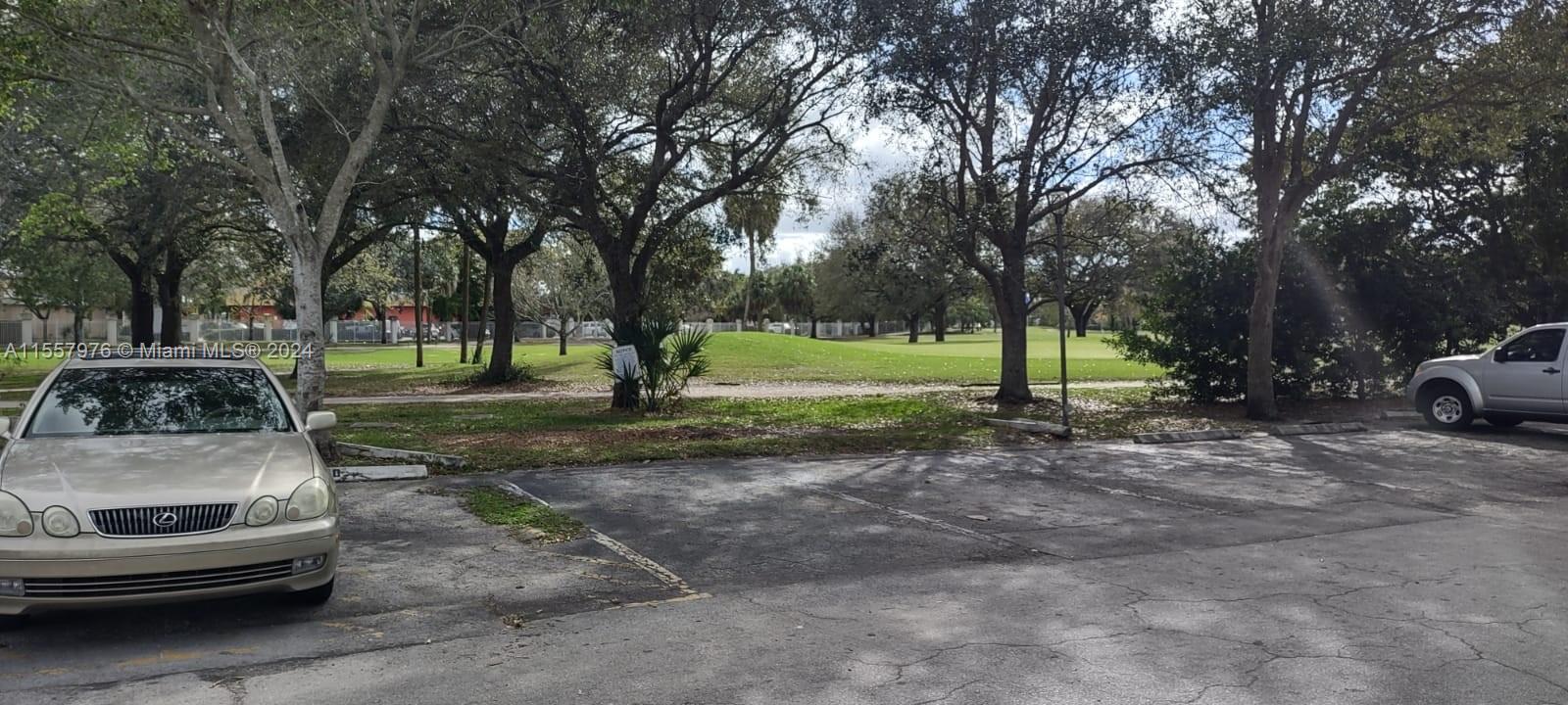 a view of a park with lots of cars parked on the road