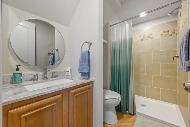 a bathroom with a granite countertop sink a toilet and shower