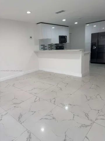 a view of a kitchen with kitchen island a sink stainless steel appliances and cabinets